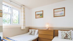 A bedroom with two single beds, a bedside table with a lamp, a window with curtains, and two framed landscape paintings on the wall. - 3 bedroom accommodation in Pickering (Pickering)