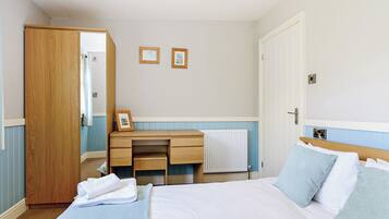 Une chambre d’hôtel avec un lit, un bureau en bois, un radiateur et une porte.