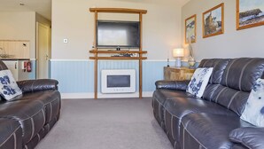 A living room with a television, fireplace, and two leather sofas. - 3 bedroom accommodation in Pickering (Pickering)