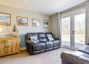 A living room with a leather sofa, wooden cabinet, and a view of the outdoors through a glass door. - 3 bedroom accommodation in Pickering (Pickering)