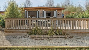 A wooden deck with outdoor seating, a covered patio area, and a gravel ground. - 3 bedroom accommodation in Pickering (Pickering)
