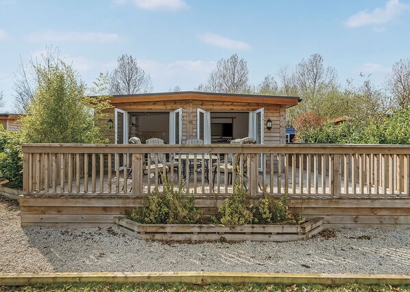 A wooden deck with outdoor seating, a covered patio area, and a gravel ground.