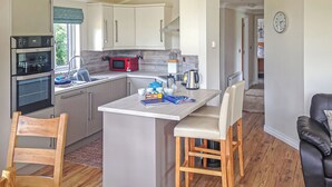 Una cocina moderna con una isla central, electrodomésticos integrados y un comedor con una silla y una mesa.
