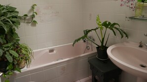 Un baño con bañera, lavamanos y varias plantas en macetas.
