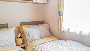 Een slaapkamer met twee bedden, een hoofdeinde en een raam met gordijnen.