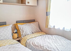 A bedroom with two beds, a headboard, and a window with curtains.