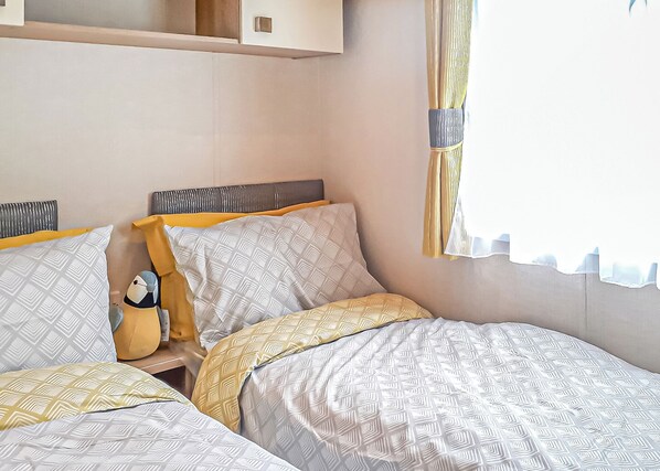 Une chambre avec deux lits, une tête de lit et une fenêtre avec des rideaux.