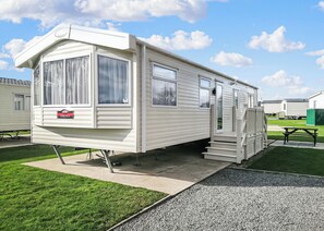 A mobile home with a covered porch, a sliding door, and a small set of steps leading to the entrance.