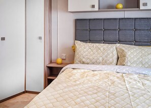 Een slaapkamer met een bed, nachtkastje, lamp en een garderobe.