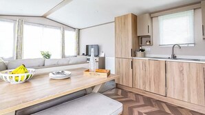 A modern kitchen with wooden cabinets, a dining table with a bench, and a large window.
