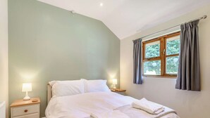 Une chambre à coucher avec un lit, des tables de chevet et une fenêtre avec des rideaux.