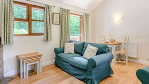 Une pièce chaleureuse avec un canapé vert, une table en bois et une fenêtre avec des rideaux.