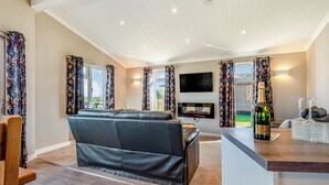 A modern living room with a sofa, a flat-screen TV, and a bottle of champagne on a table. - 1 bedroom accommodation in Shrewsbury (Shrewsbury)
