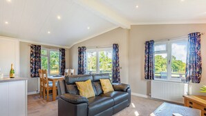 A modern living room with a black leather sofa, a wooden coffee table, and a dining area with a table and chairs. - 1 bedroom accommodation in Shrewsbury (Shrewsbury)