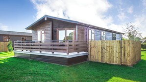 A modern single-story house with a deck, a wooden fence, and a well-maintained lawn. - 1 bedroom accommodation in Shrewsbury (Shrewsbury)