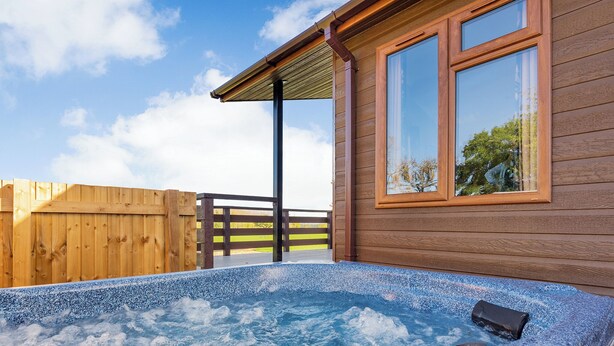 A wooden cabin with a hot tub, wooden deck, and a wooden fence. - 1 bedroom accommodation in Shrewsbury (Shrewsbury)