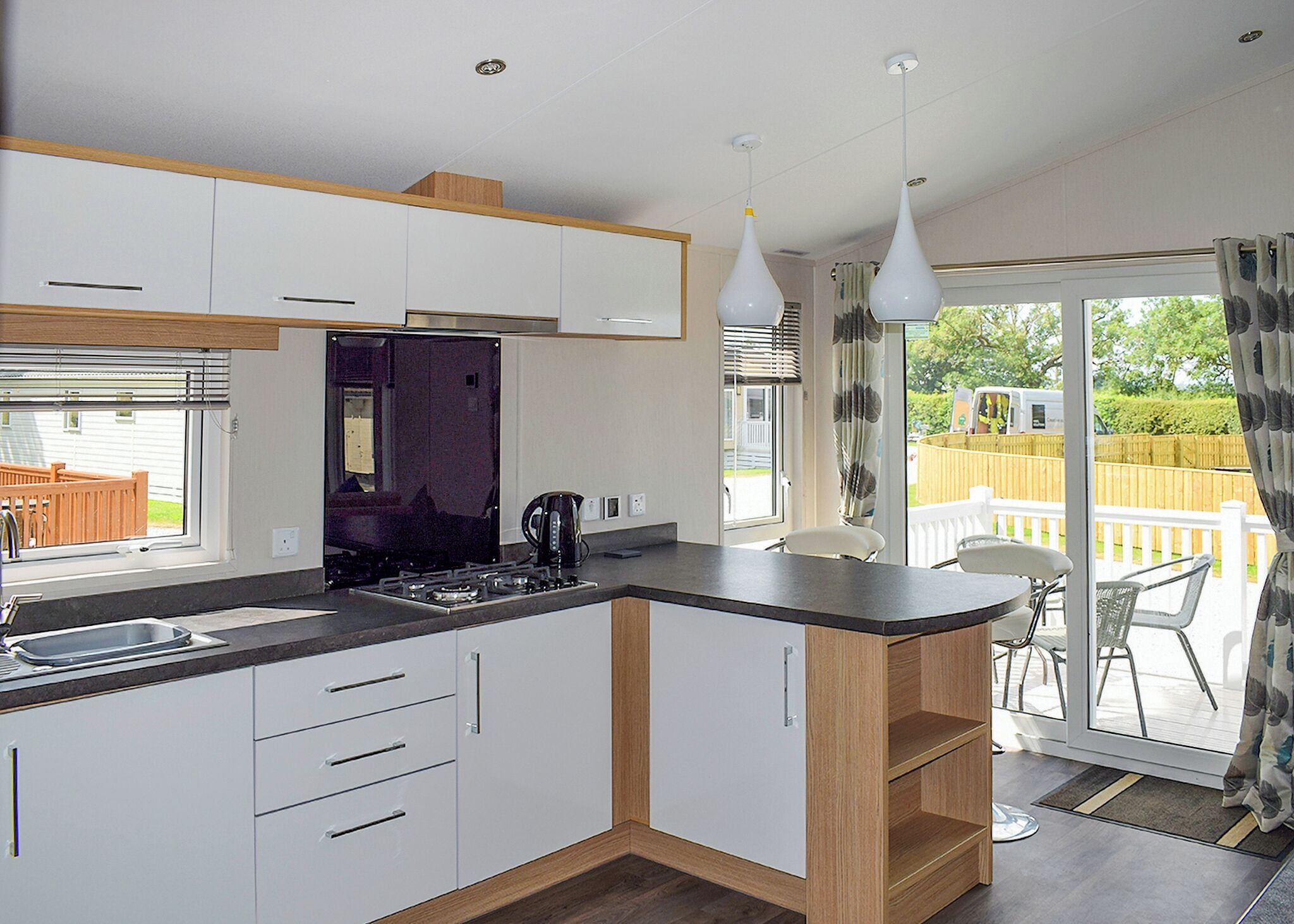 A modern kitchen with white cabinets, a black countertop, and a built-in stove. There is a dining area with a table and chairs outside the kitchen.