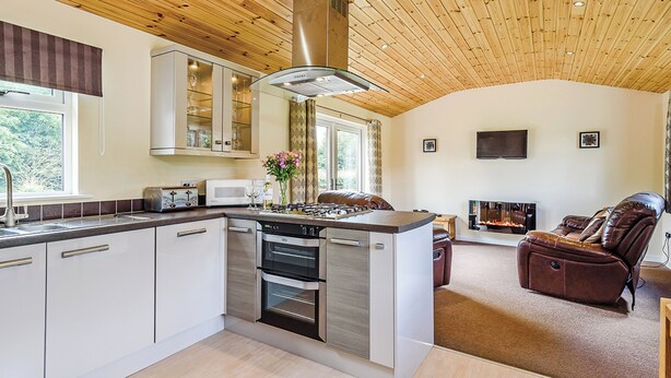 A modern kitchen with wooden ceiling, built-in cabinets, and a central island. - Luxury lodge with king-size bed with en suite shower. (Shrewsbury)