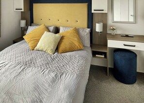 A neatly arranged hotel room with a bed, bedside tables, a desk, and a trash bin.