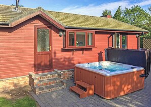 A red wooden building with a hot tub, a door, and a window.