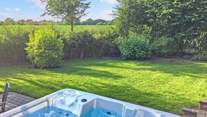 A hot tub in a backyard with a grassy lawn and trees.