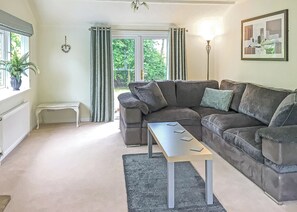 A living room with a sectional sofa, a small table, a bench, a radiator, a potted plant, and a framed picture on the wall. - 3 bedroom accommodation in Easingwold (Easingwold)