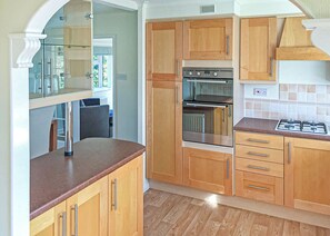 A kitchen with wooden cabinets, a built-in oven, and a gas stove. - 3 bedroom accommodation in Easingwold (Easingwold)