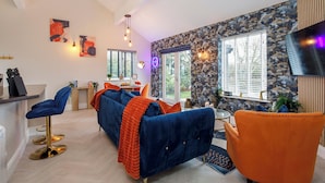 A modern living room with a blue sofa, an orange armchair, and a glass coffee table. - 1 bedroom accommodation in South Duffield, Nr York (South Duffield, Nr York)