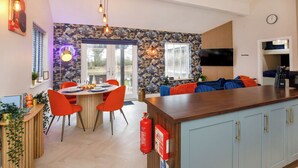 A modern kitchen with a stone backsplash, a dining area with orange chairs, and a built-in TV. - 1 bedroom accommodation in South Duffield, Nr York (South Duffield, Nr York)