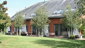 A modern building with a sloped roof, large windows, and a well-maintained lawn.