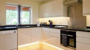 A modern kitchen with white cabinets, a black countertop, and a stainless steel range hood.