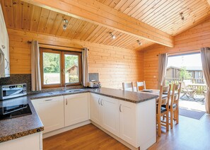 Une cuisine avec des meubles en bois, un plan de travail en granit et une fenêtre avec des rideaux.