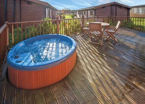 Ein Whirlpool auf einer Holzterrasse mit einem Tisch und Stühlen in der Nähe.
