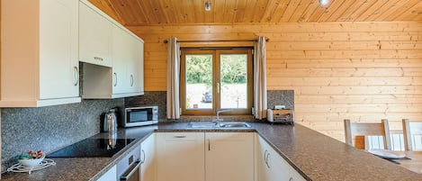 A compact kitchen with white cabinets, a granite countertop, a microwave, and a sink.