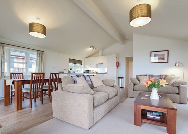 A modern living room with a sofa, a coffee table, and a dining area with chairs and a table.