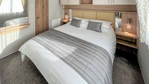 Un dormitorio con cama, mesitas de noche, un espejo y armarios empotrados de madera.