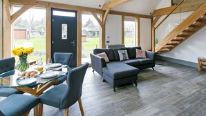 Un amplio espacio habitable con un sofá moderno, una mesa de comedor con sillas y una escalera.