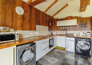 A kitchen with wooden walls, a toaster, a washing machine, and a clock. - Luxurious and stylish modern lodge with one master double and one twin. (Haswell, Nr Durham)