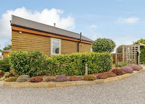 A log cabin with a window, surrounded by well-maintained hedges and a gravel driveway. - Luxurious and stylish modern lodge with one master double and one twin. (Haswell, Nr Durham)