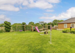 A backyard with a wooden play structure, a slide, and a swing set. - Luxurious and stylish modern lodge with one master double and one twin. (Haswell, Nr Durham)