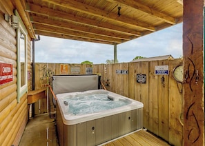 Una cabaña de madera con jacuzzi, paredes de madera y un porche cubierto.