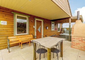 A wooden cabin with a dining area, a bench, and a fireplace.