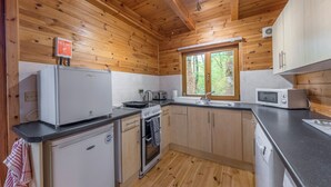Een kleine keuken met houten wanden, een raam en eenvoudige apparaten.