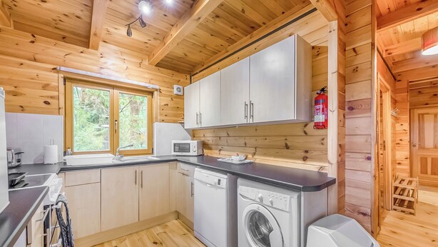 Een houten cabinemeubilair met een keukenhoek, inclusief een magnetron, spoelbak en wasmachine.