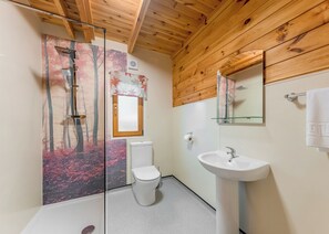 Une salle de bain moderne avec une douche à parois de verre, des toilettes, un lavabo et un plafond en bois.