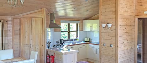 Interior de una cabaña de madera con comedor, cocina y un sofá morado.