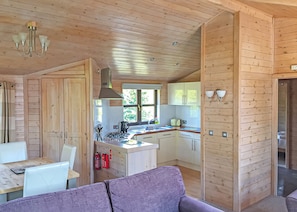 A wooden cabin interior with a dining area, kitchen, and a purple sofa. - 2 bedroom accommodation in Easingwold (Easingwold)