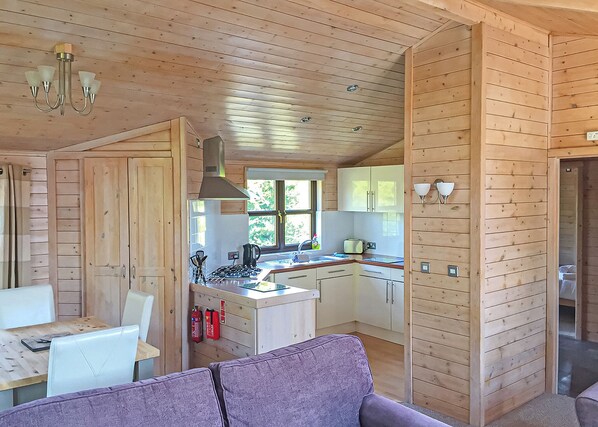 L’intérieur d’un chalet en bois comprend un coin repas, une cuisine et un canapé violet.