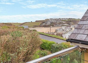 A coastal town with a beach, houses, and a road leading to it. - Spacious and stylish villa with beach views. (Porth, Nr Newquay)