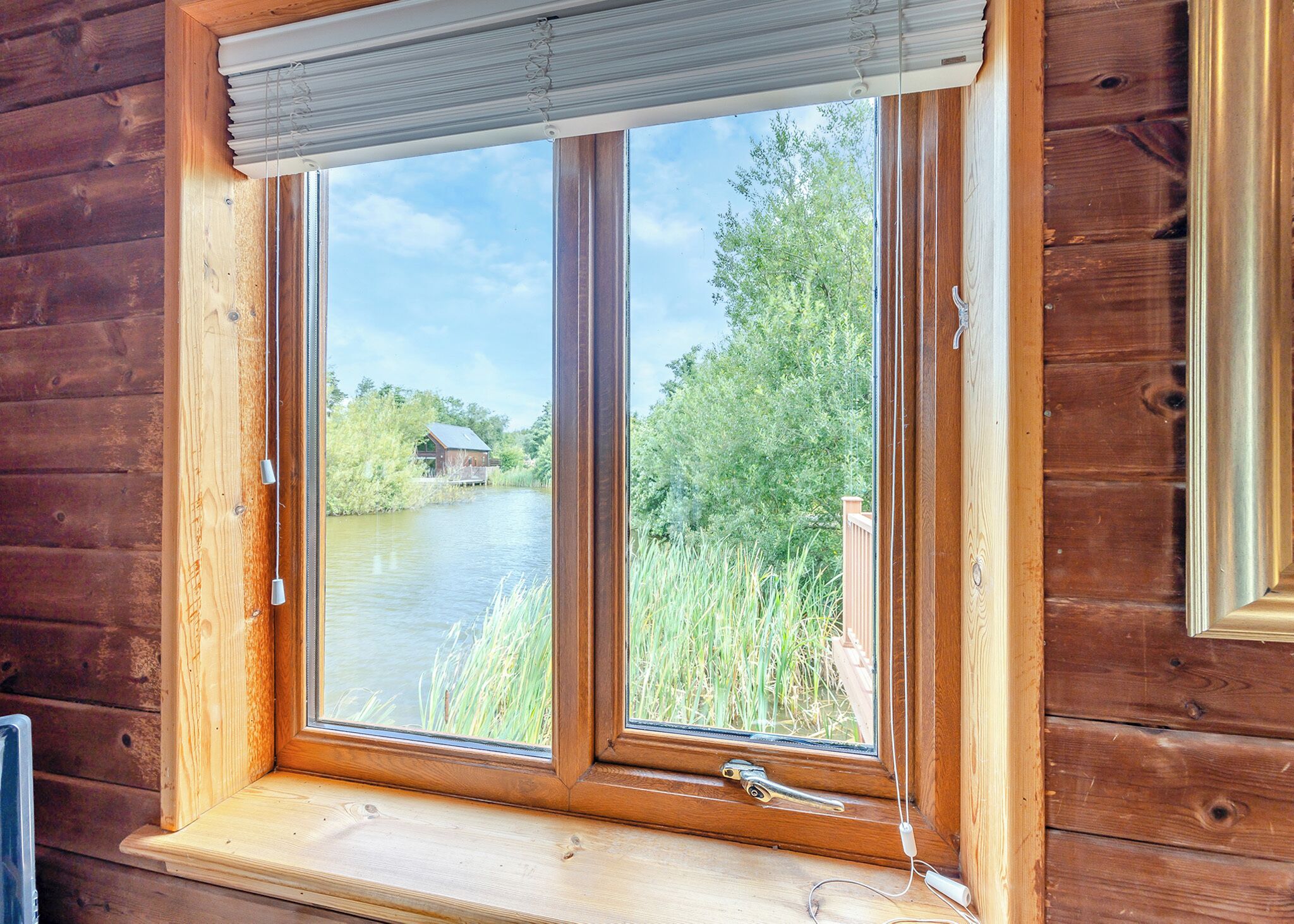Eine Holzhütte mit einem Fenster, das auf einen Fluss und grüne Vegetation blickt.